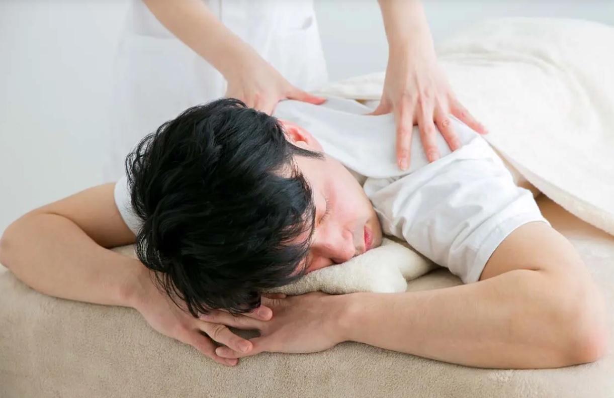 Praticien effectuant un massage Tuina traditionnel chinois sur une personne volontaire